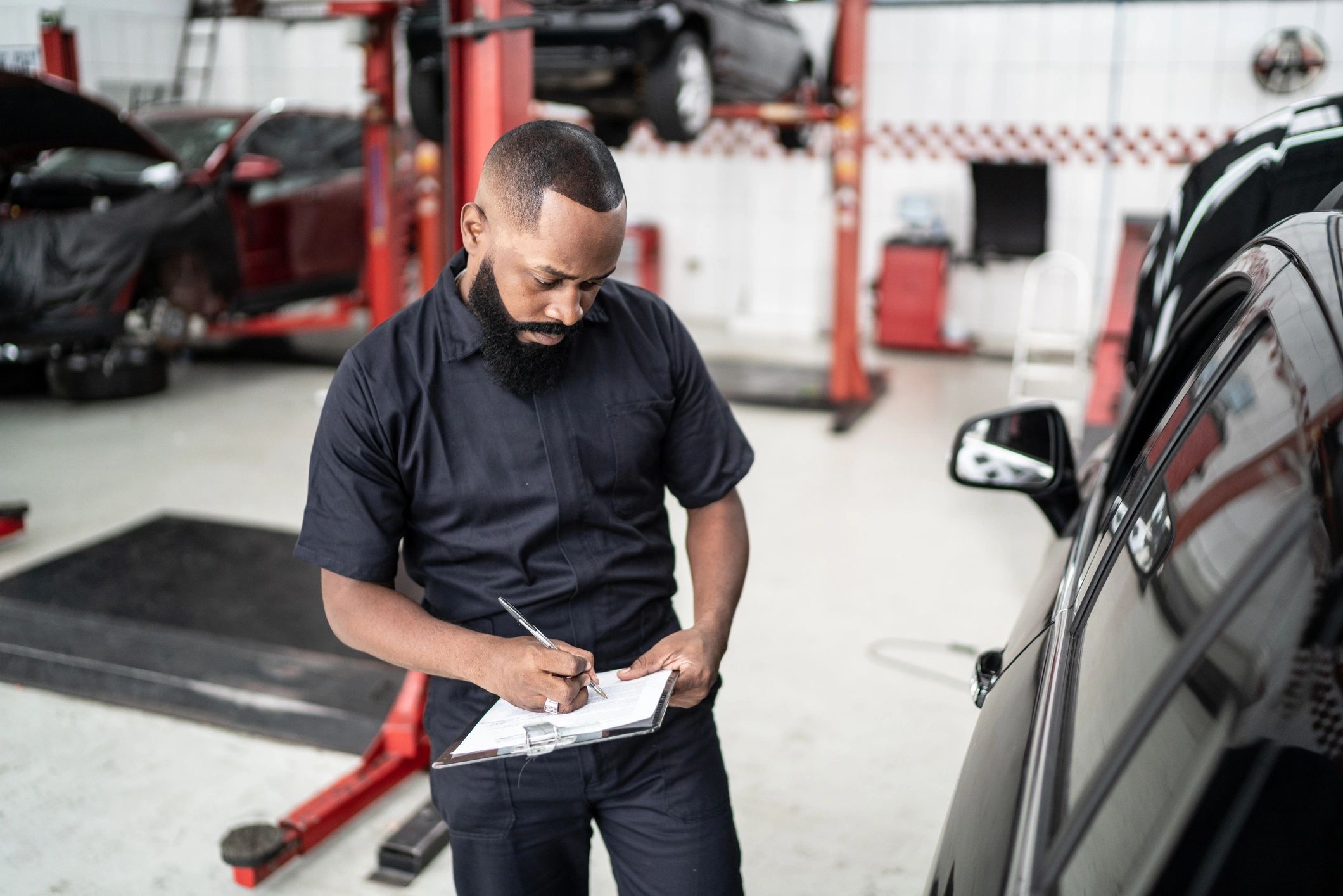 Technician in an auto shop reviewing a checklist on a clipboard