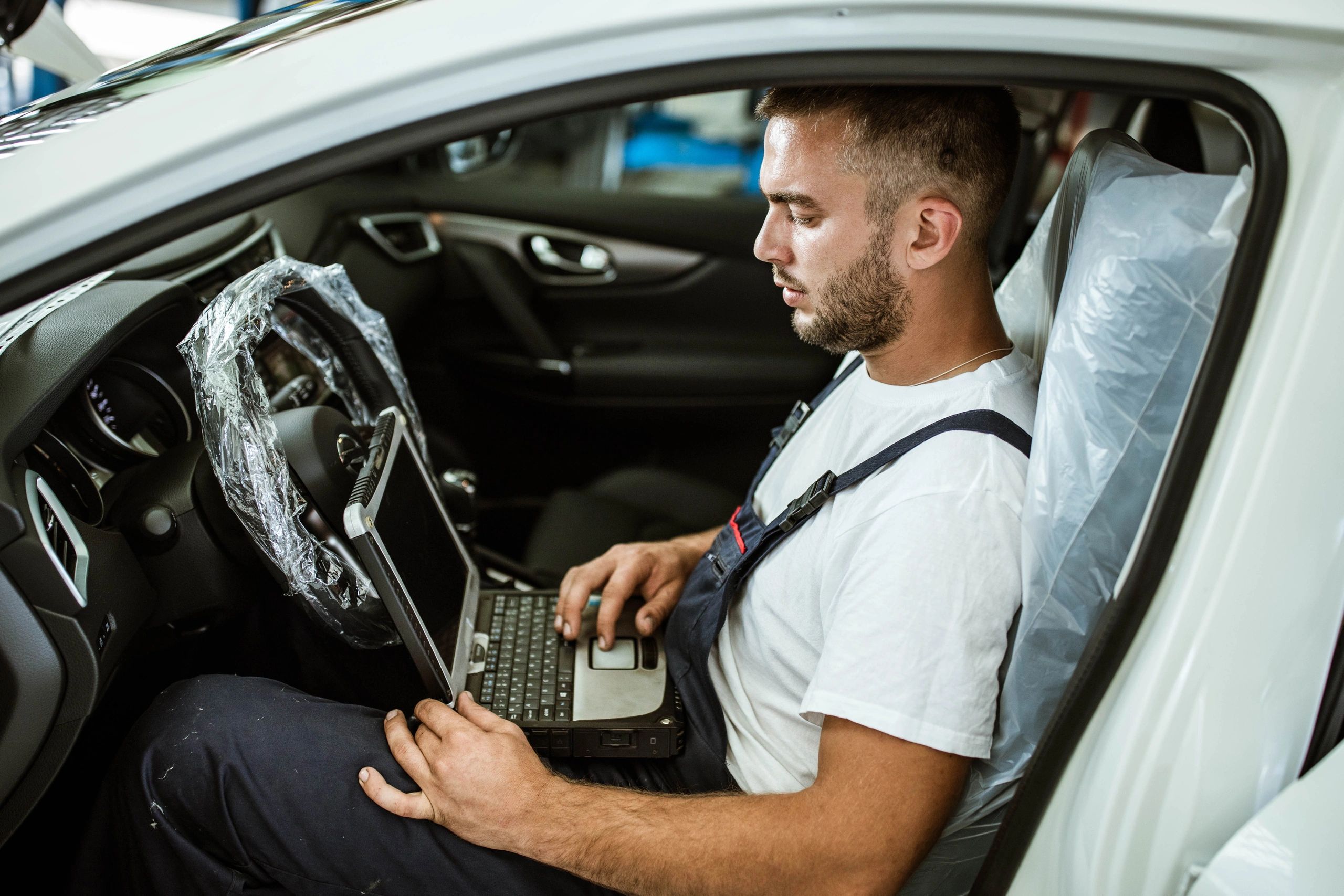 Technician using a laptop to test a vehicle in a workshop.
