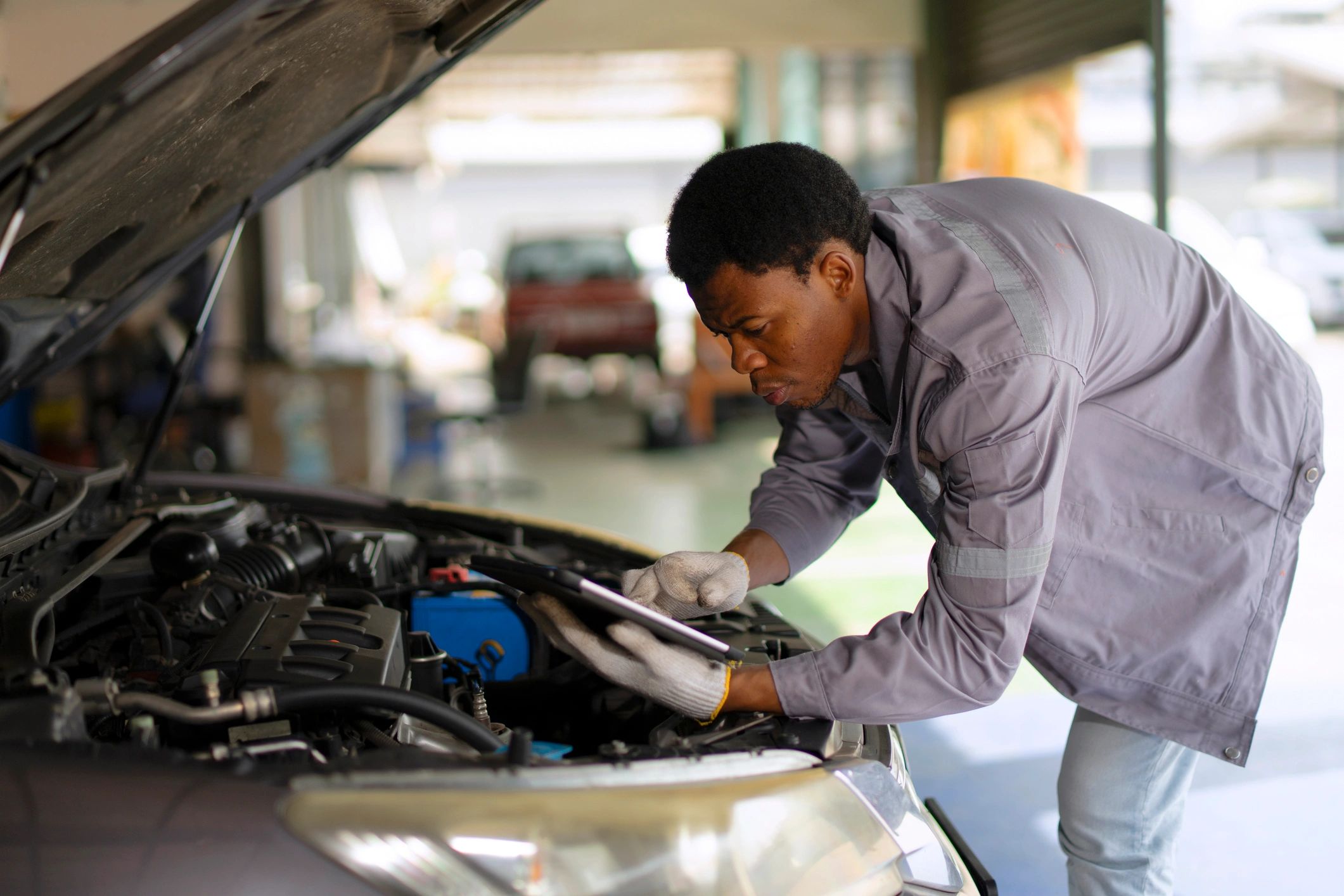 Mechanic inspecting a car engine in a service bay