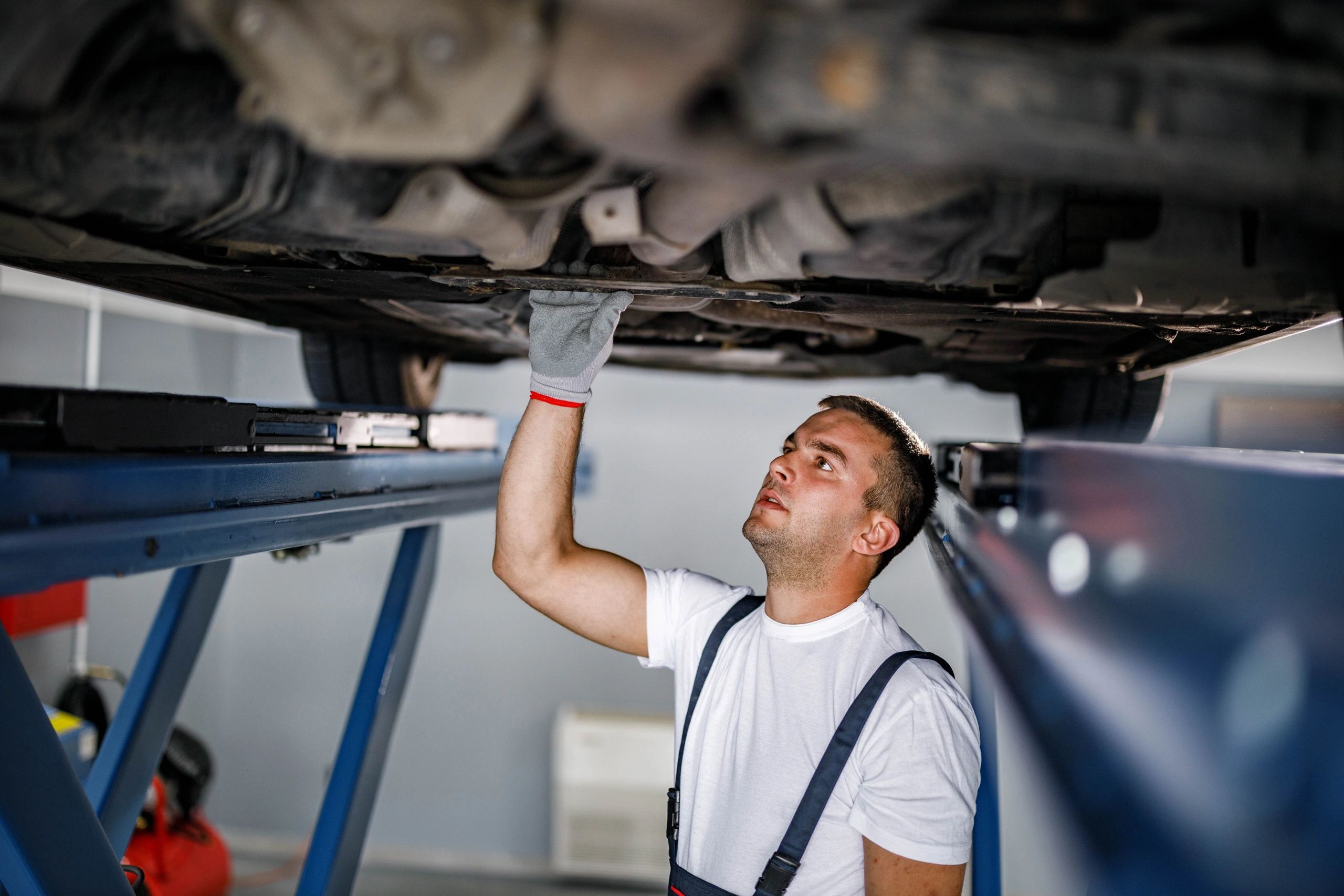Technician working under a vehicle in an auto repair shop