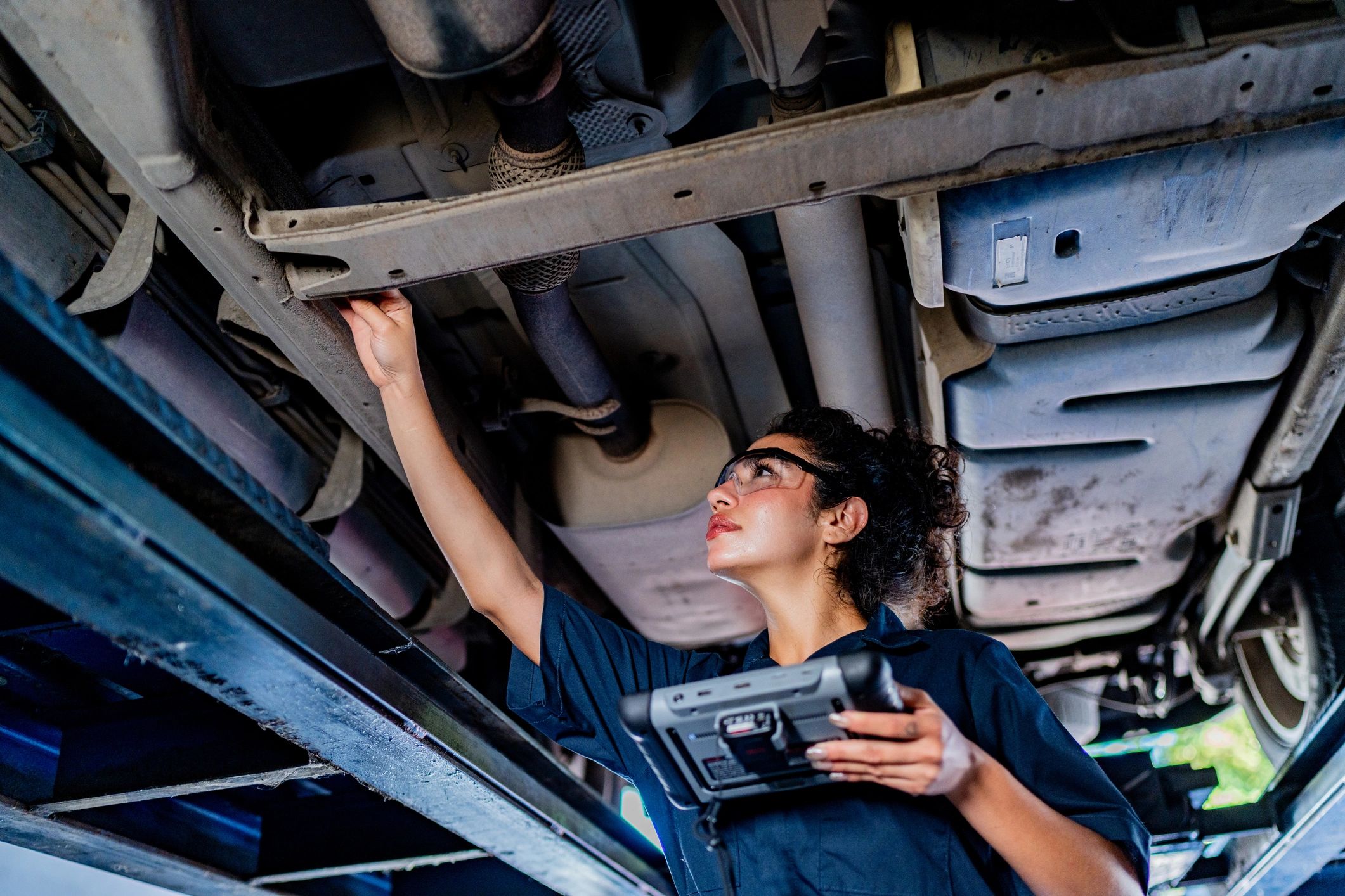 Mechanic inspecting a vehicle on a lift during transmission service